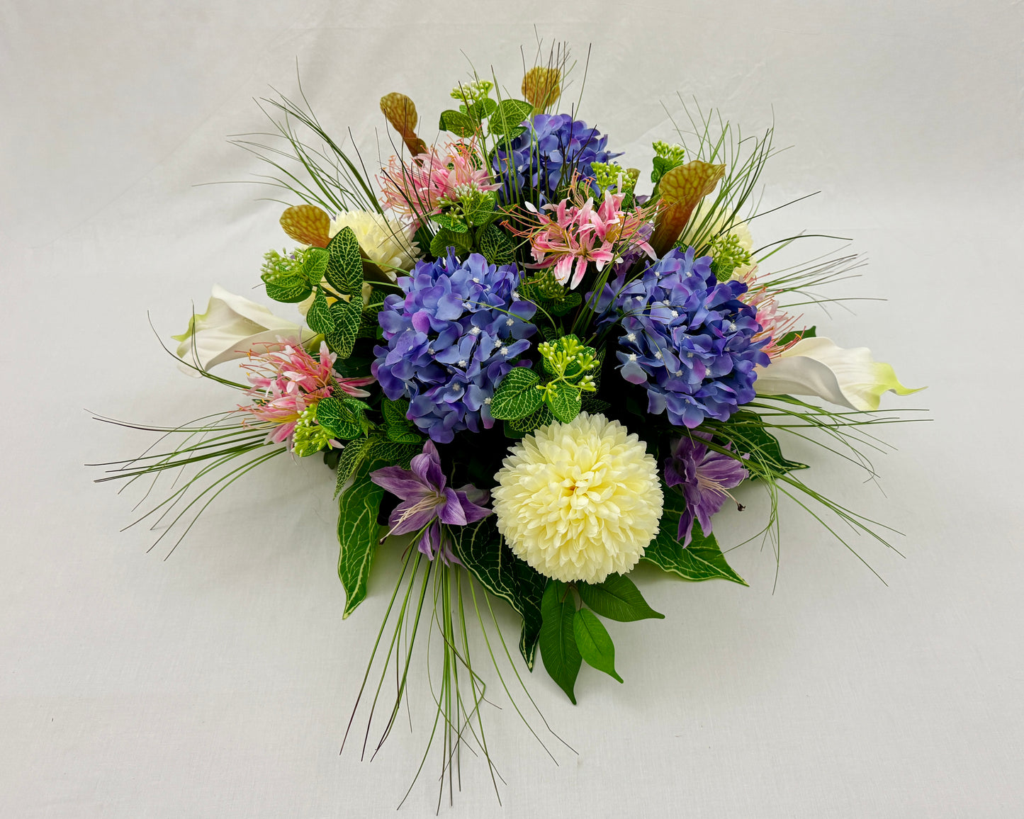 Rond rouwstuk van roze en paarse bloemen