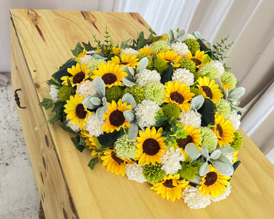 Rouwhart van zonnebloemen op grafkist