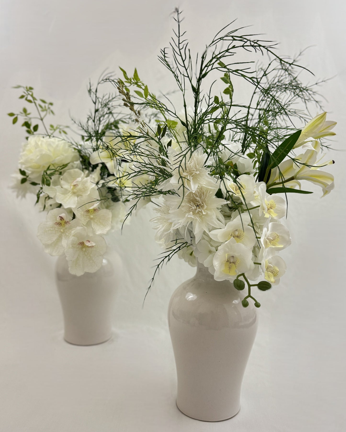 2 gelijke rouwboeketten met witte bloemen in vaas