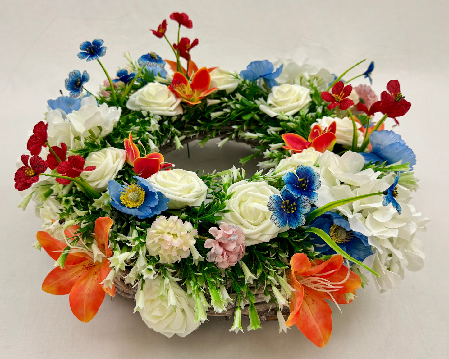 Rouwkrans van rode, witte en blauwe bloemen van voren gezien