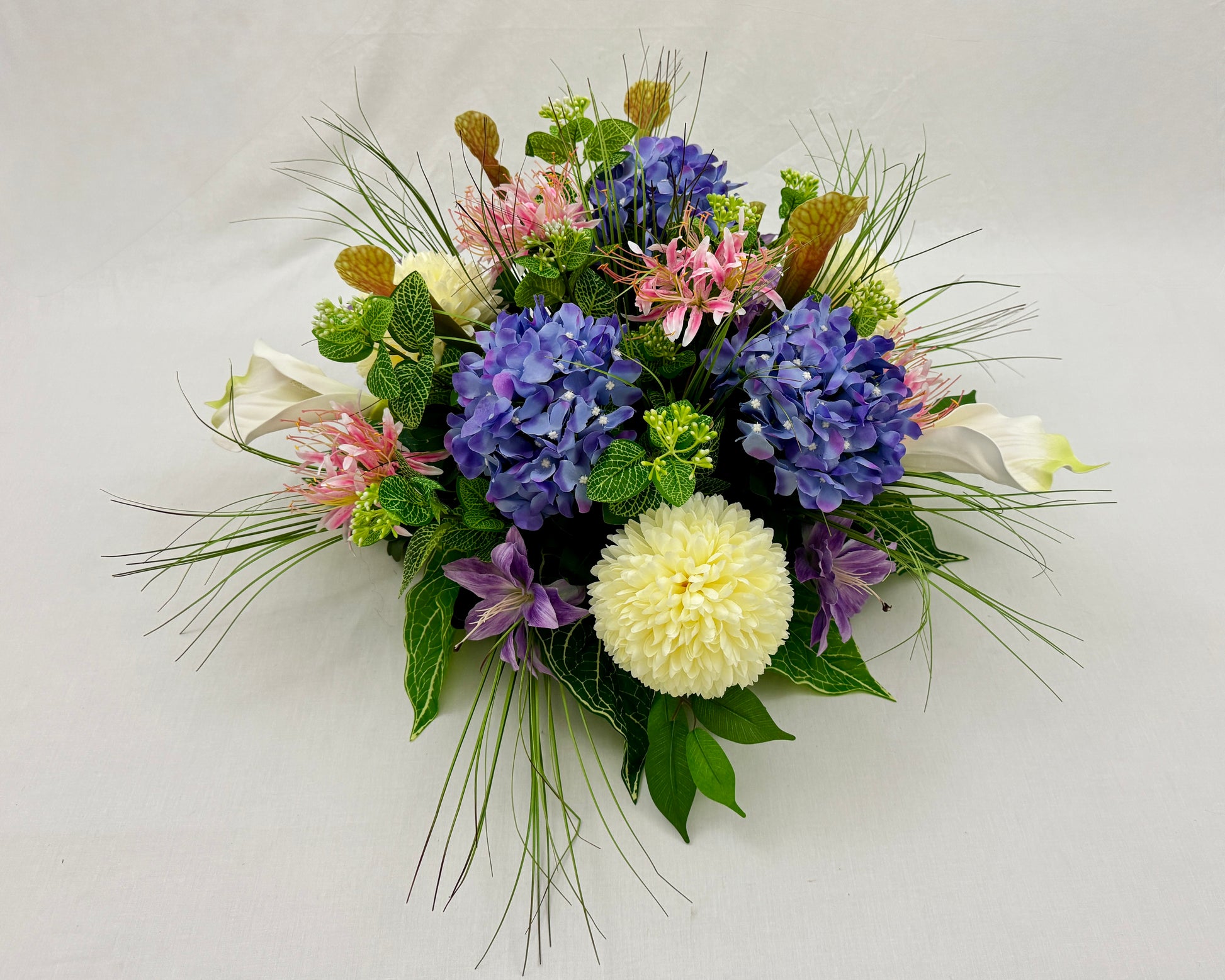 Rond rouwstuk van roze en paarse bloemen