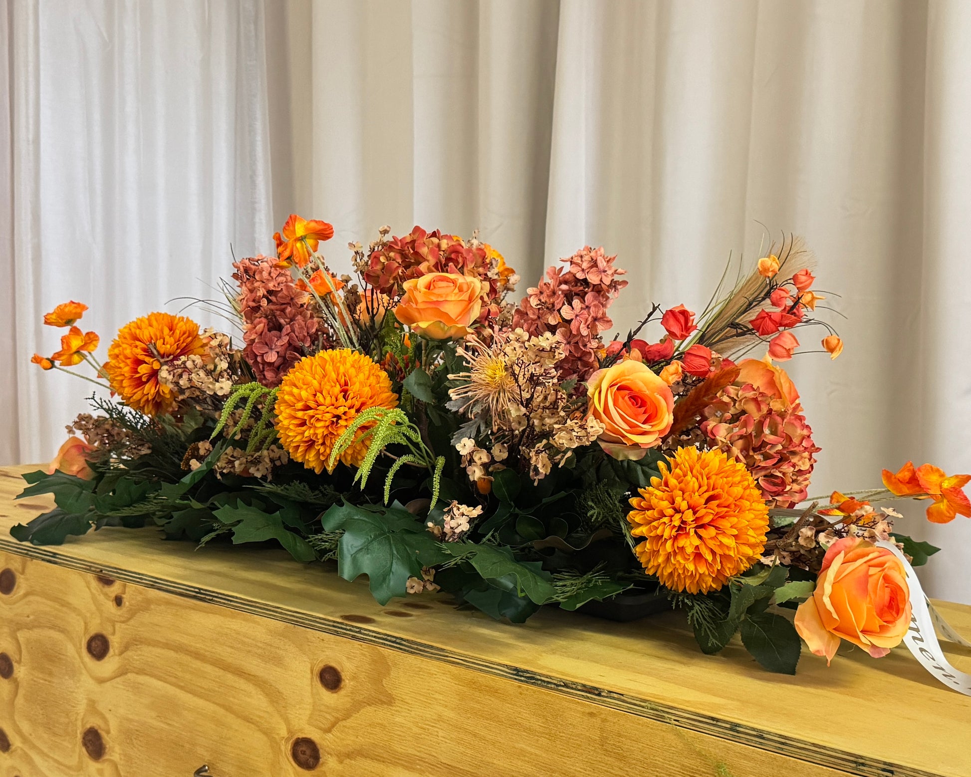 Rouwkist met oranje bloemstuk