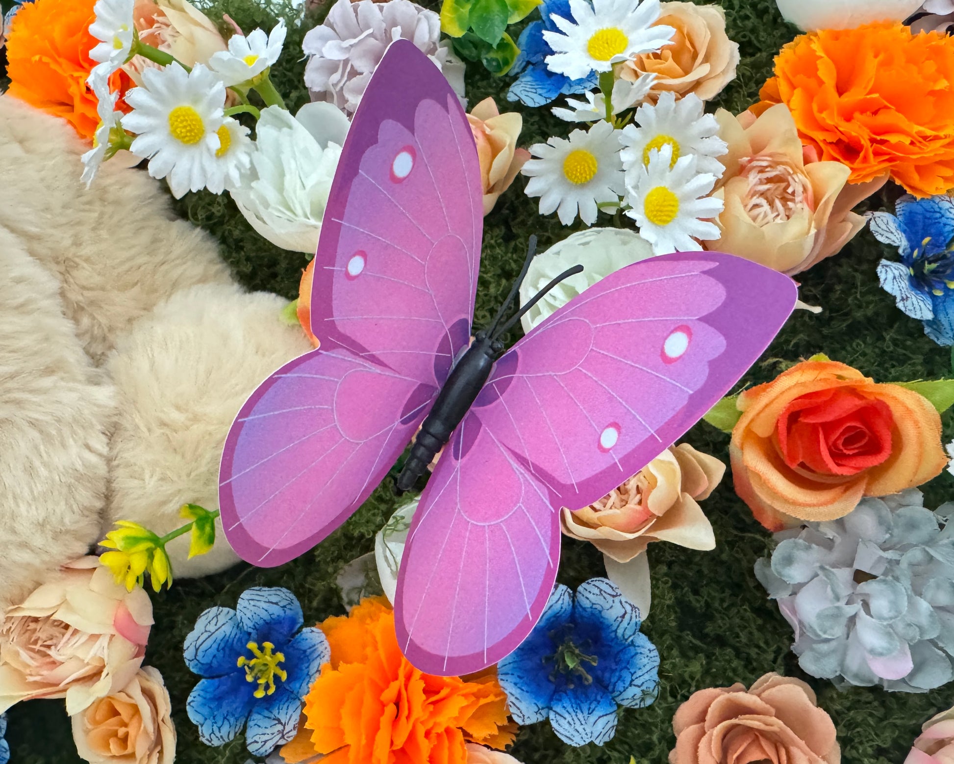 Close up van rouwstuk voor kind met bloemen, vlinders en een teddybeer