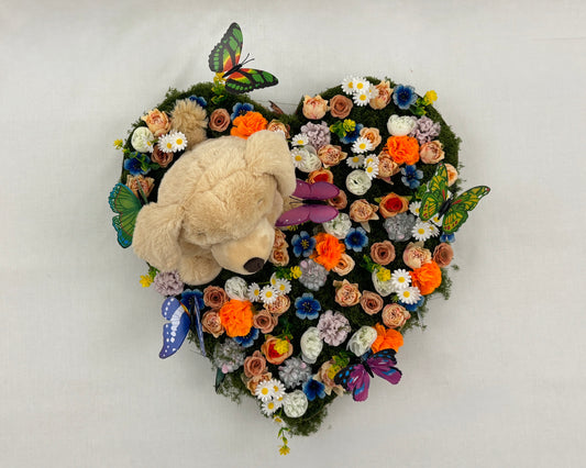 Rouwstuk voor kind met bloemen, vlinders en een teddybeer van boven gezien