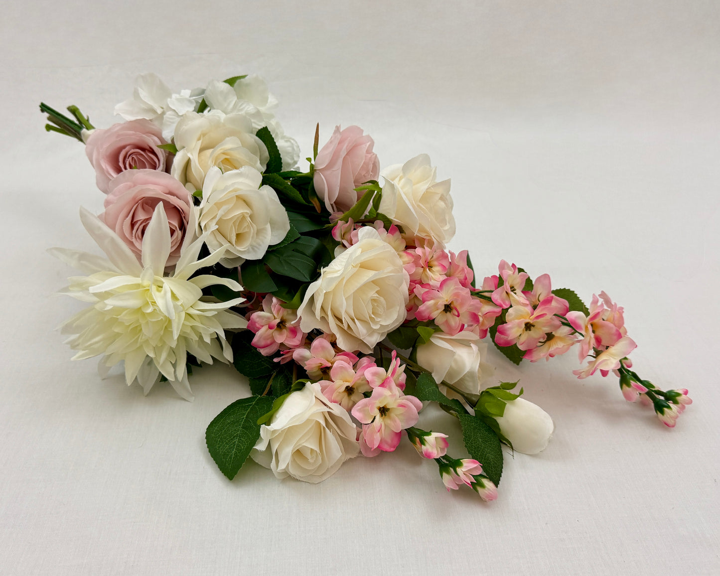 Liggend rouwboeket met roze en witte rozen