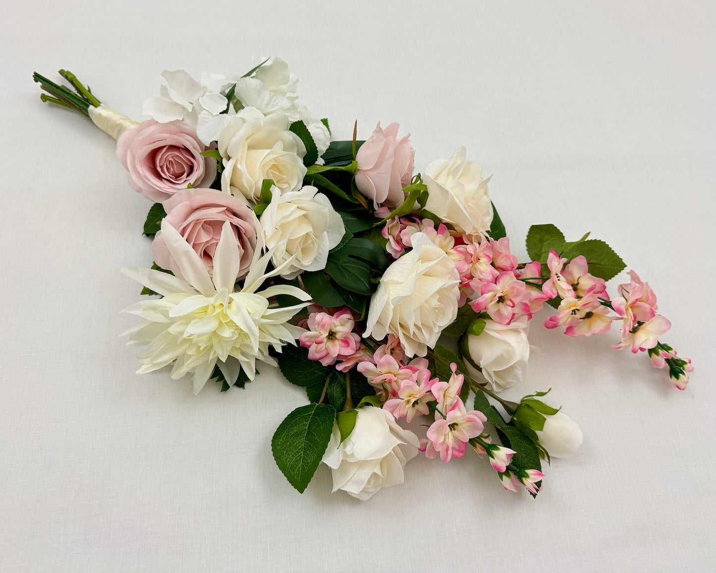 Liggend rouwboeket met roze en witte rozen