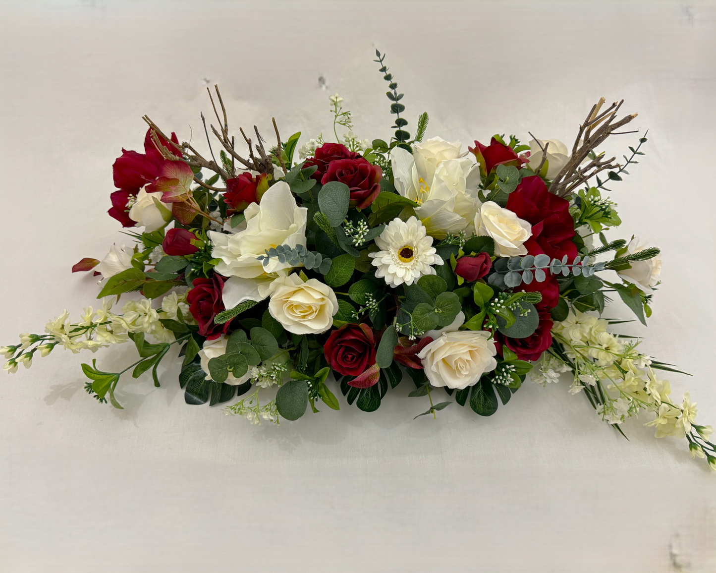 Langwerpig rouwstuk met rode amarylissen en witte rozen