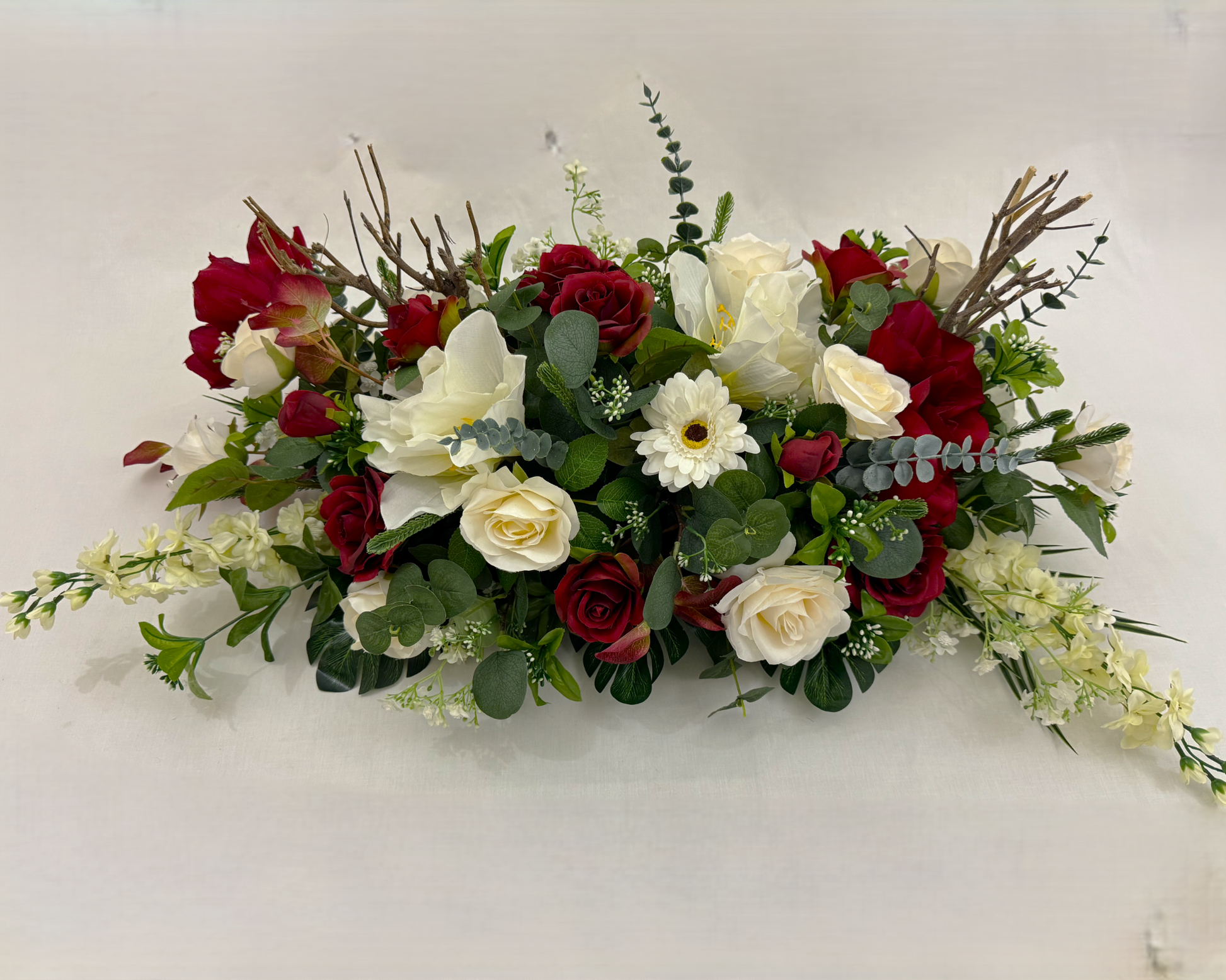 Langwerpig rouwstuk met rode amarylissen en witte rozen