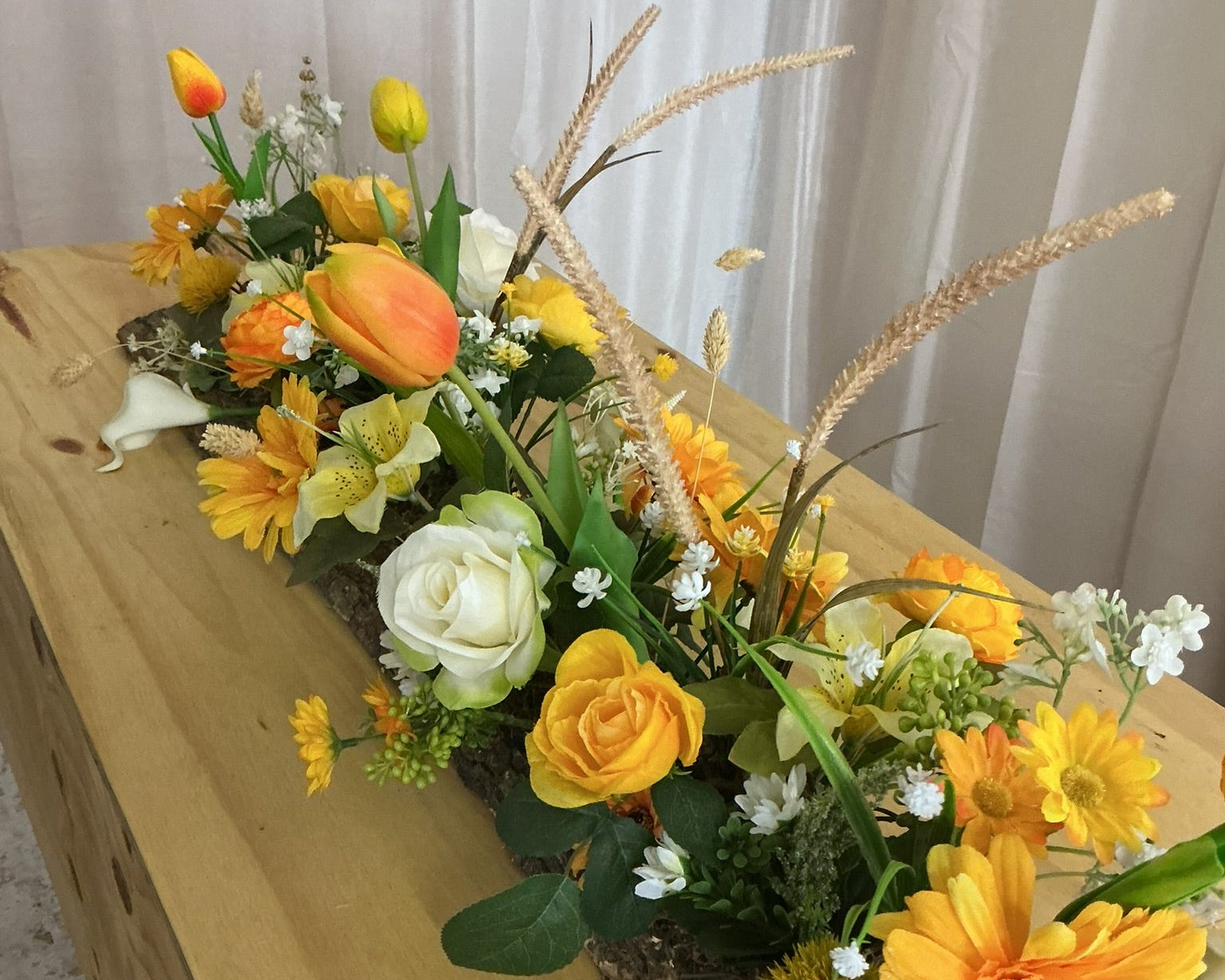 Rouwstuk op kist met gele bloemen