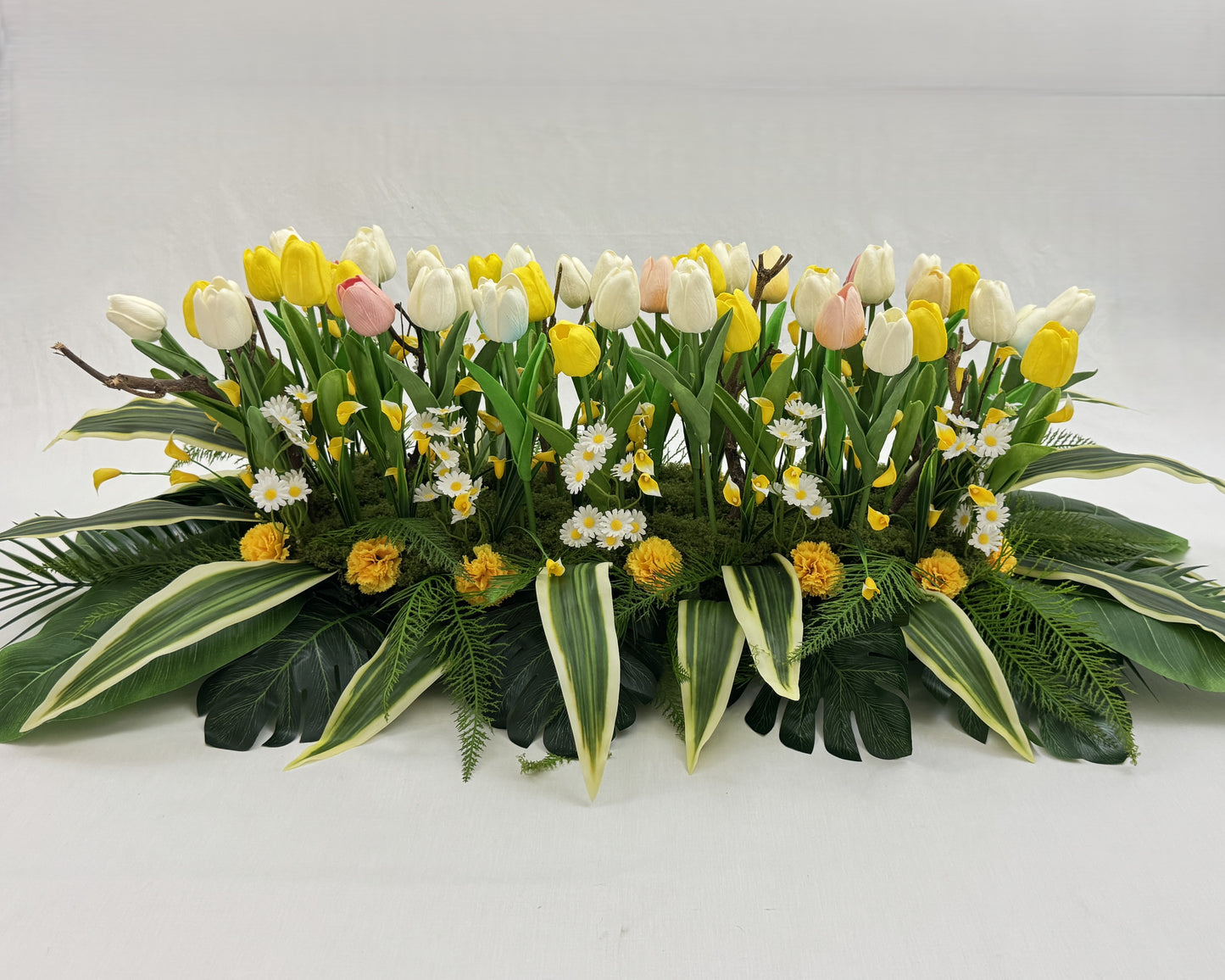 Langwerpig rouwstuk met tulpen en madeliefjes