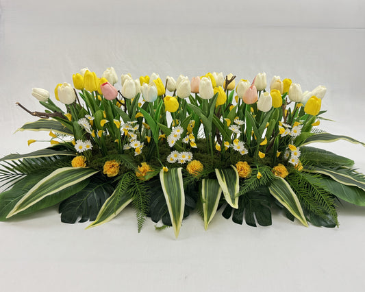 Langwerpig rouwstuk met tulpen en madeliefjes