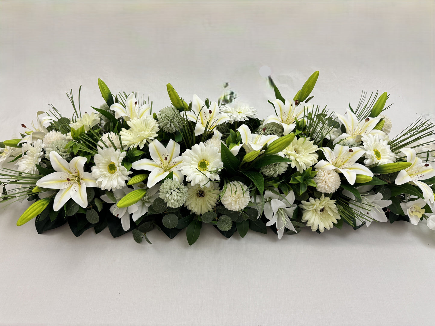 Close-up van langwerpig rouwstuk met witte bloemen