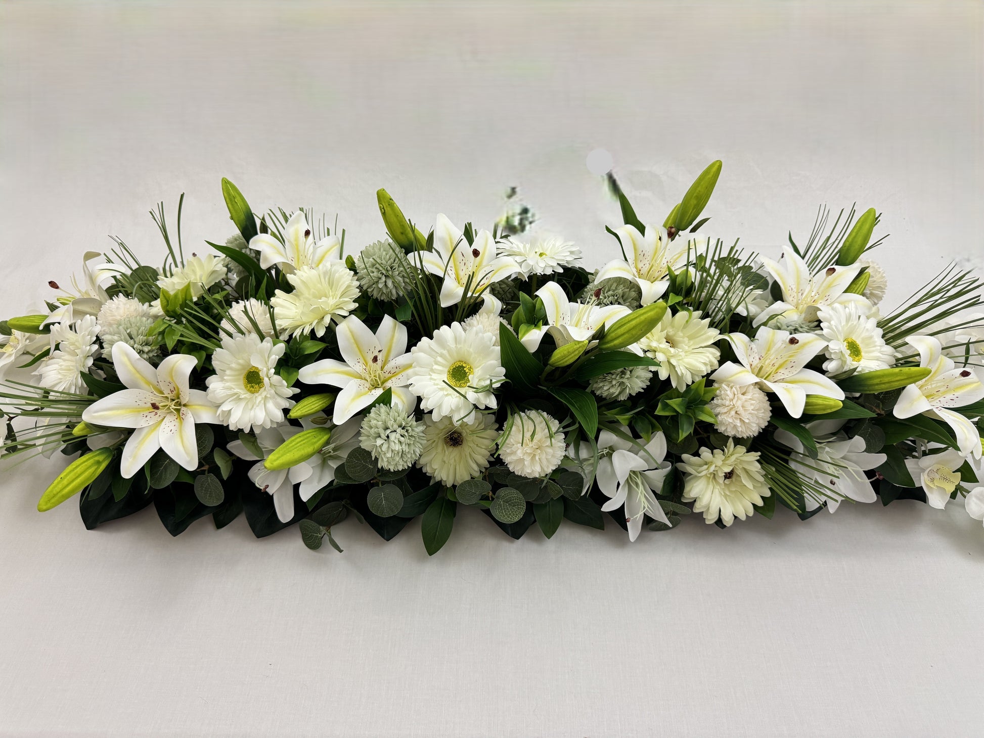 Close-up van langwerpig rouwstuk met witte bloemen