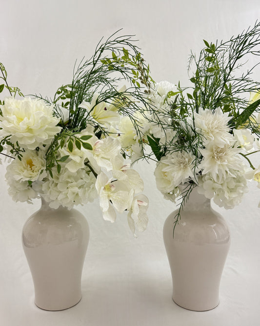 2 symmetrische rouwboeketten met witte bloemen in vazen