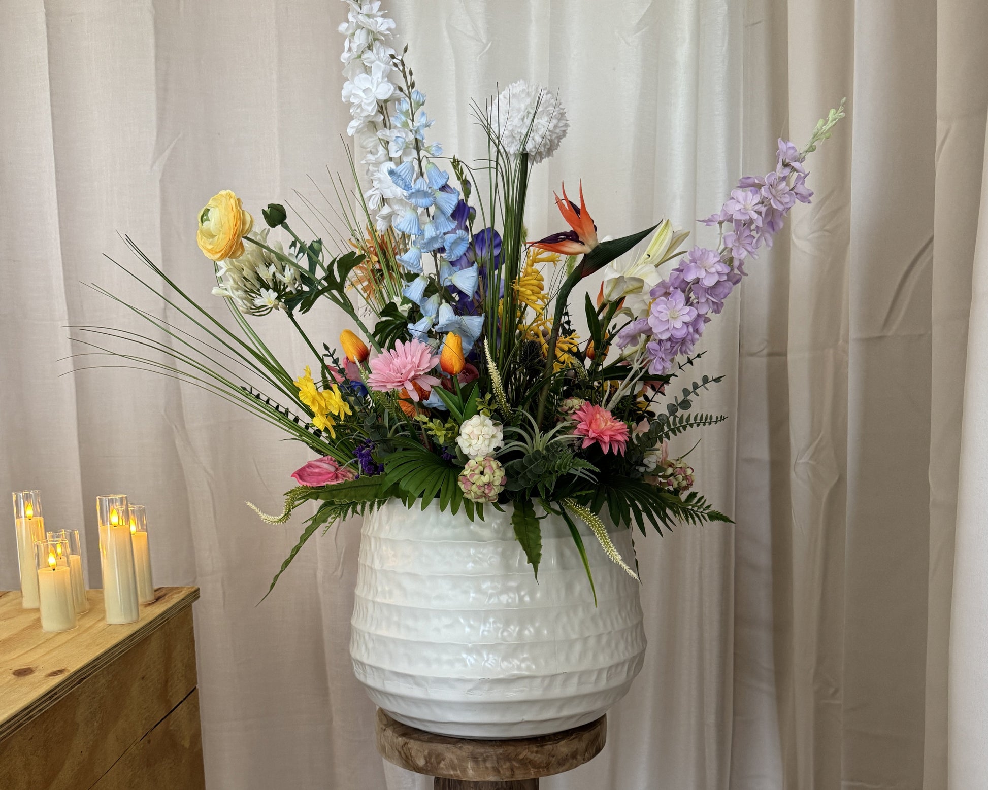 Kolossaal rouwboeket witte vaas naast kist met kaarsjes