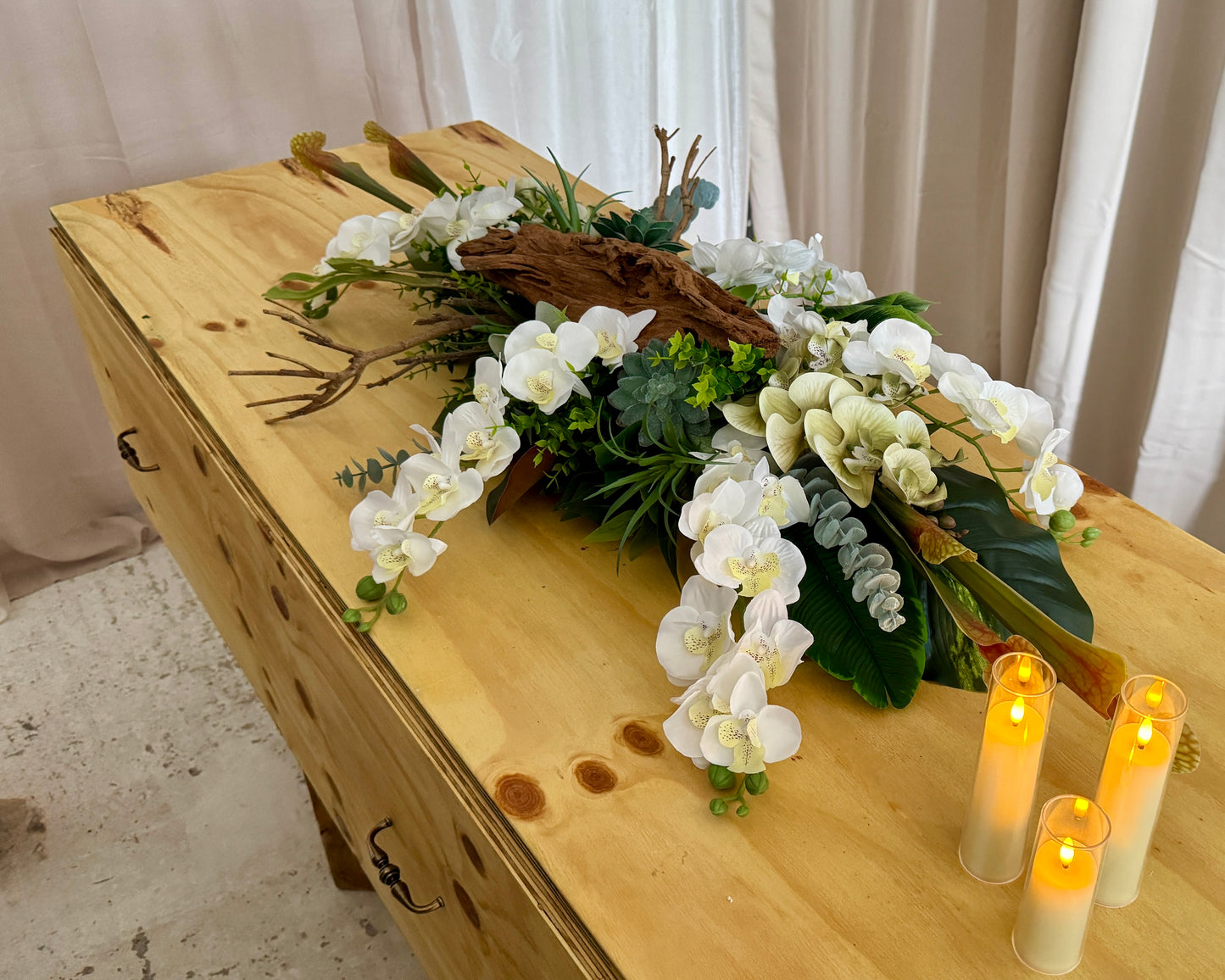 Lang kiststuk met orchideeën en hout op kist met kaarsjes