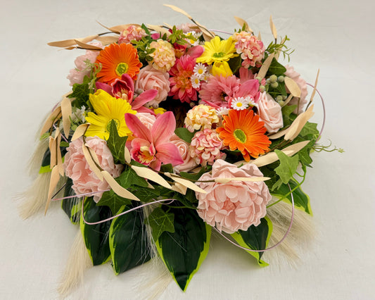 Rouwkrans in mand met kleurige bloemen