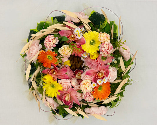 Rouwkrans in mand met kleurige bloemen