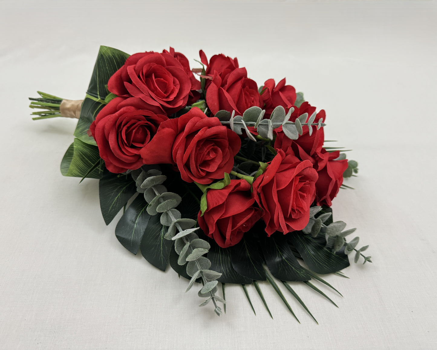 Liggend rouwboeket van rode rozen en eucalyptusbladeren