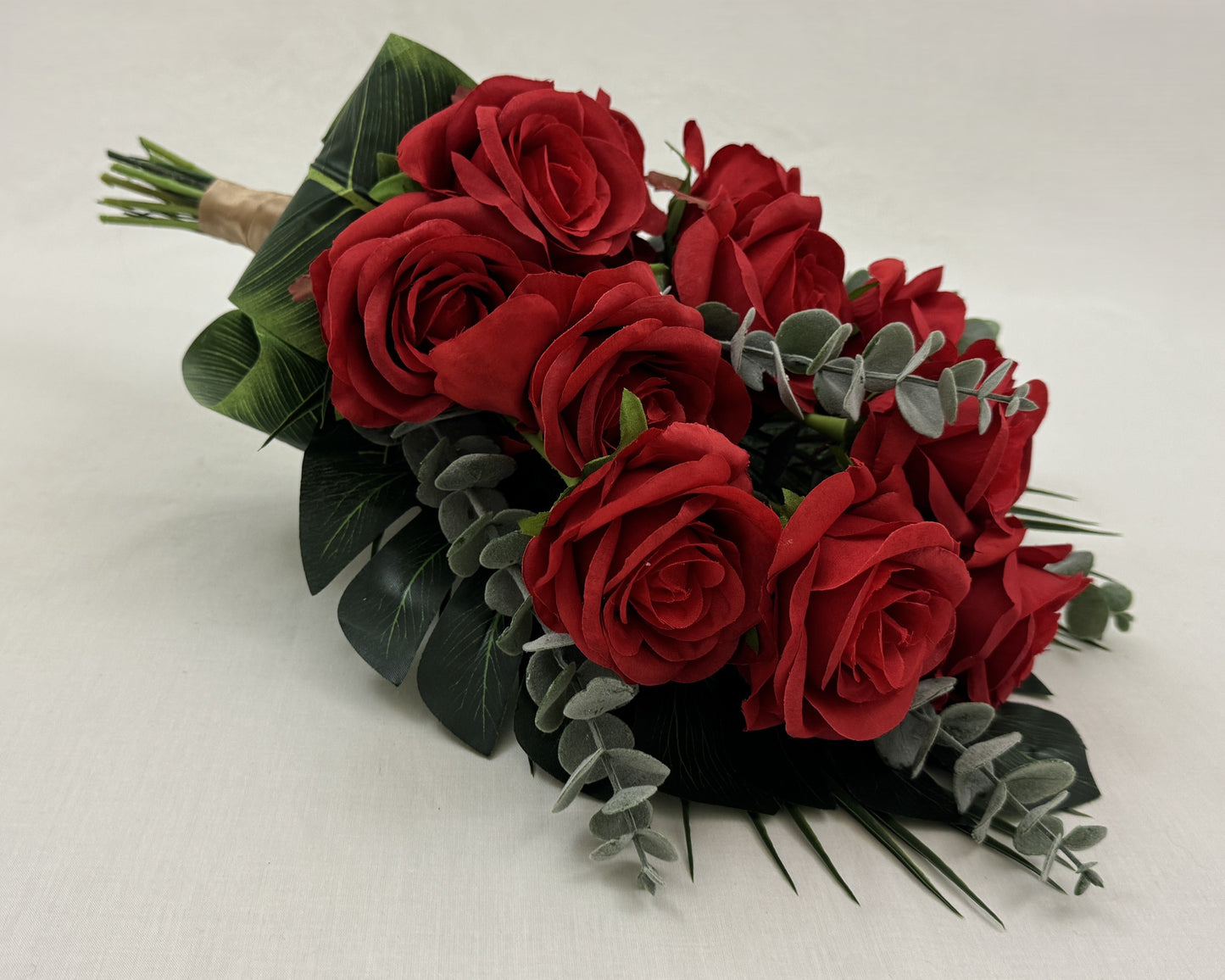 Liggend rouwboeket van rode rozen en eucalyptusbladeren