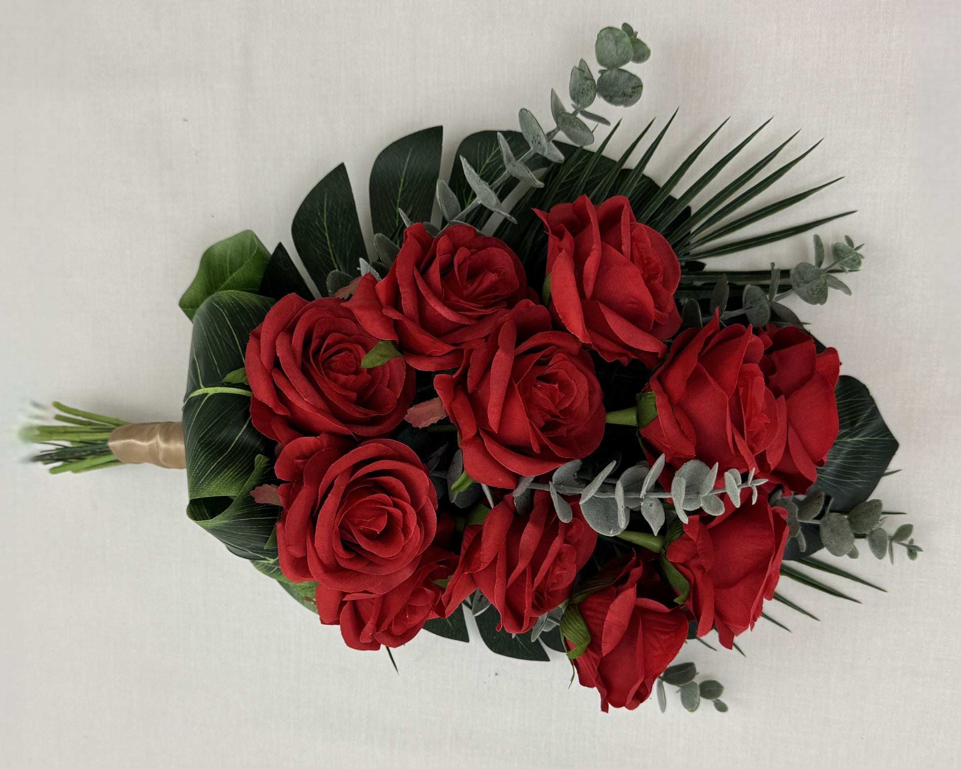 Liggend rouwboeket van rode rozen en eucalyptusbladeren getoond vanaf de bovenkant
