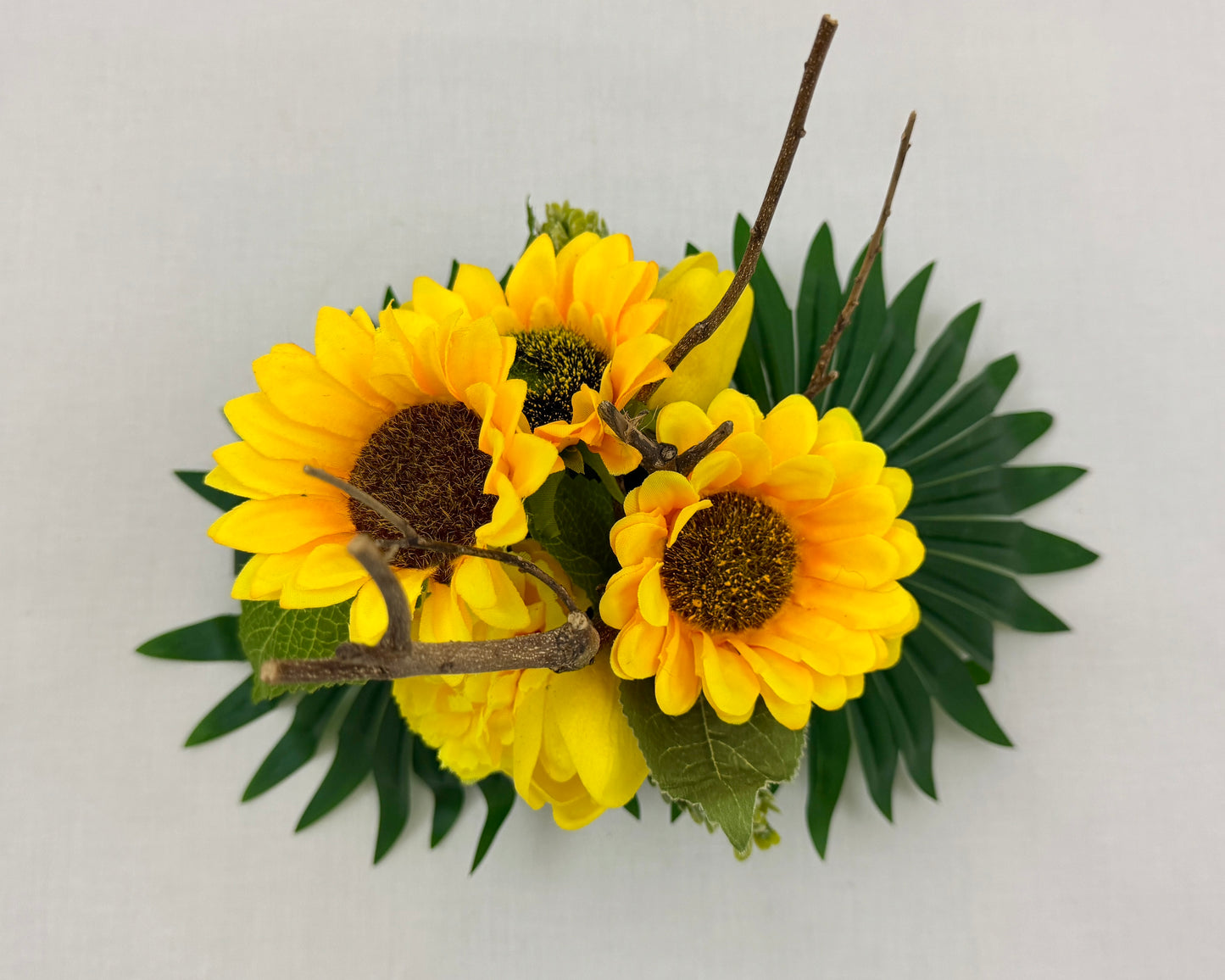 Mini rouwboeket met zonnebloemen en takje vanaf boven gezien