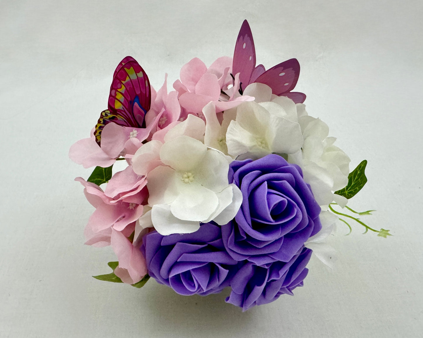 Mini rouwstuk van hortensia's en vlindertjes met paarse rozen