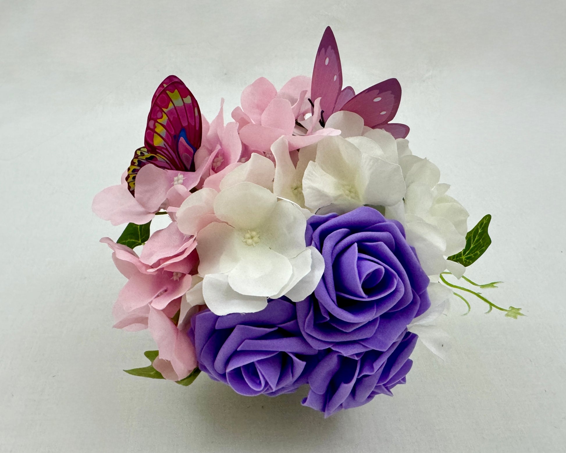 Mini rouwstuk van hortensia's en vlindertjes met paarse rozen