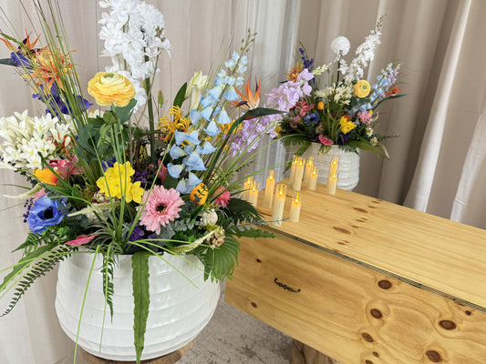 twee symmetrische gemengde veldboeketten naast grafkist