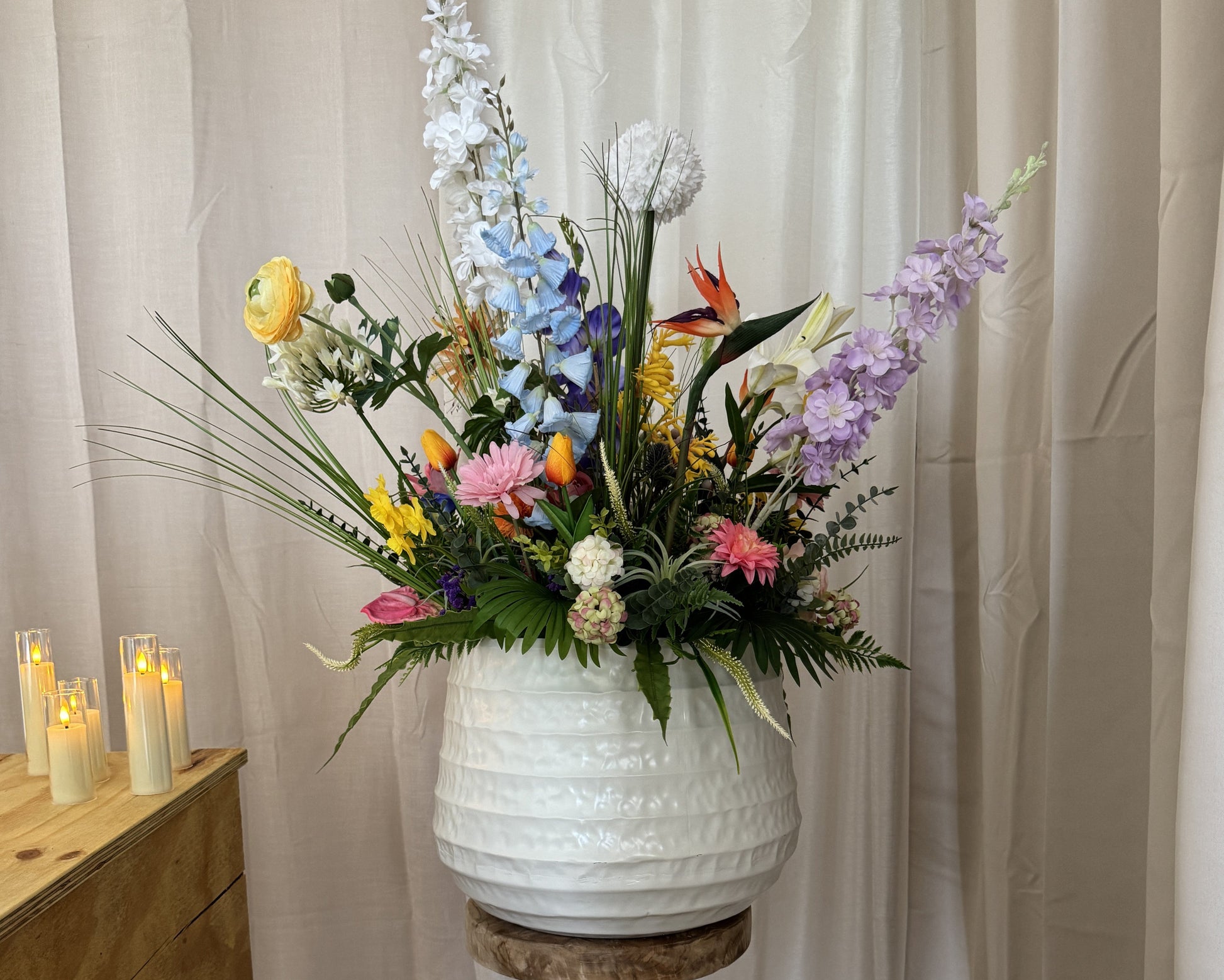 Groot rouwstuk met veldbloemen naast kist